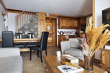 A living room with a table and chairs and a vase of flowers