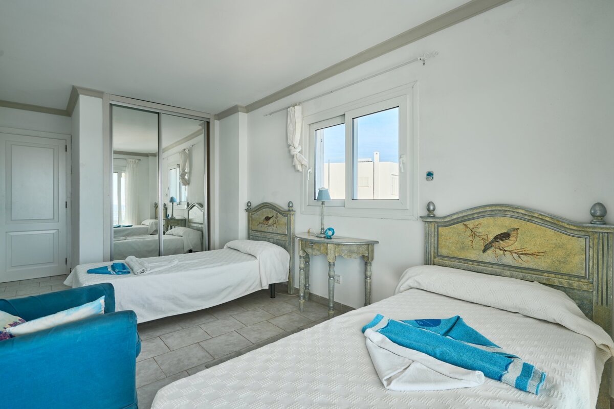 A bedroom with two beds and a blue chair