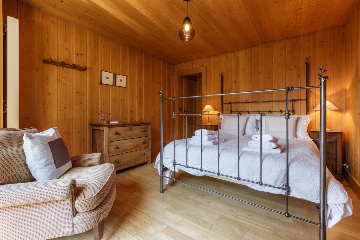 A bedroom with wood paneled walls and a bed