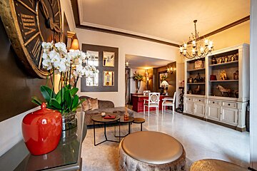 A living room with a clock on the wall that has roman numerals