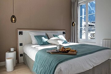 A bed in a hotel room with a tray of food on it