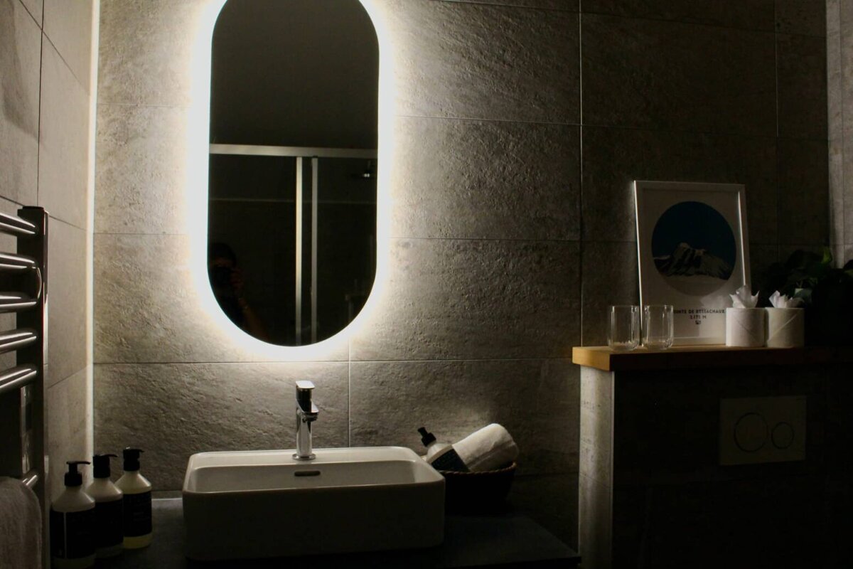 A bathroom with a sink and a lighted mirror