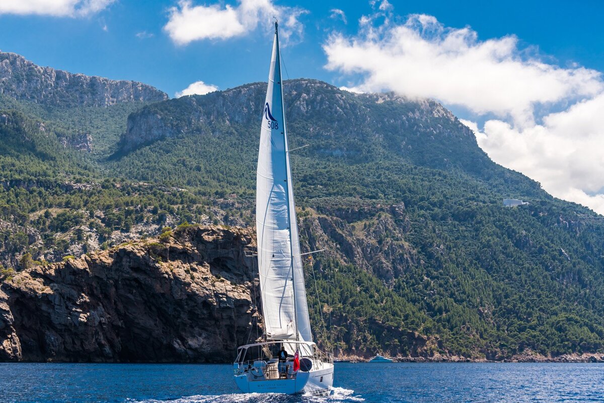 A sailboat in the ocean with mountains in the background