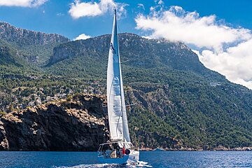 A sailboat in the ocean with mountains in the background