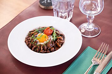 A plate of food with a tomato and an egg on a table