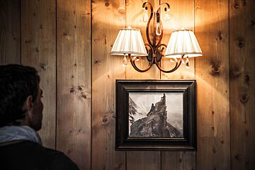 A man looks at a framed picture on a wooden wall