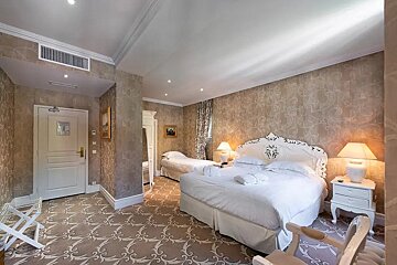 A hotel room with a large bed and two smaller beds