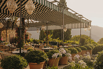 A restaurant with tables and chairs under a striped awning