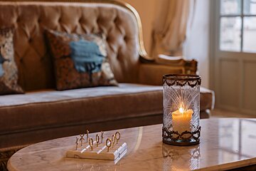 A candle in a glass holder sits on a table in front of a couch