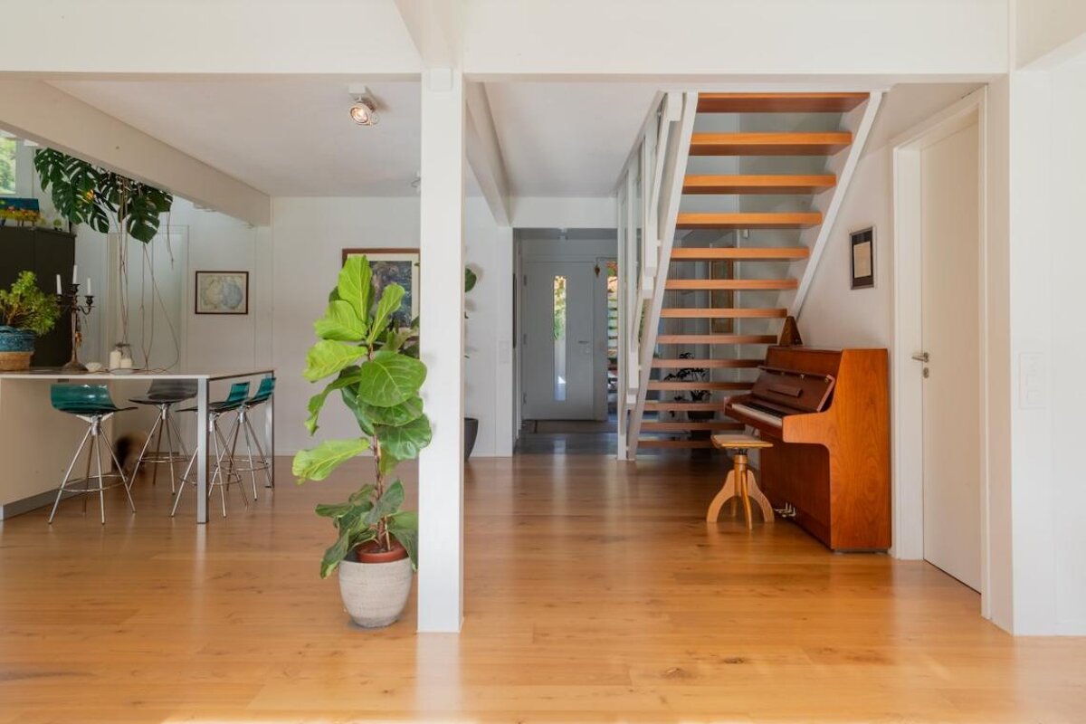 A piano sits in the middle of a room next to a staircase