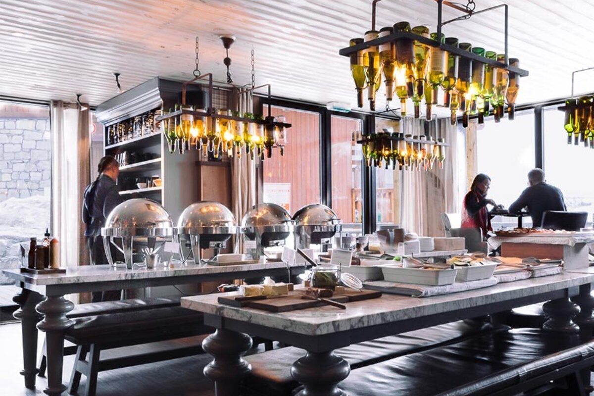 A restaurant with many tables and bottles hanging from the ceiling
