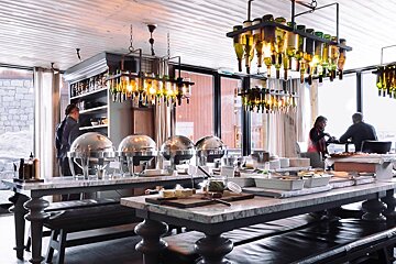 A restaurant with many tables and bottles hanging from the ceiling