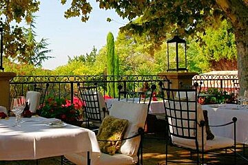 image of a terrace with lush green trees in the background and tables laid for service on the terrace