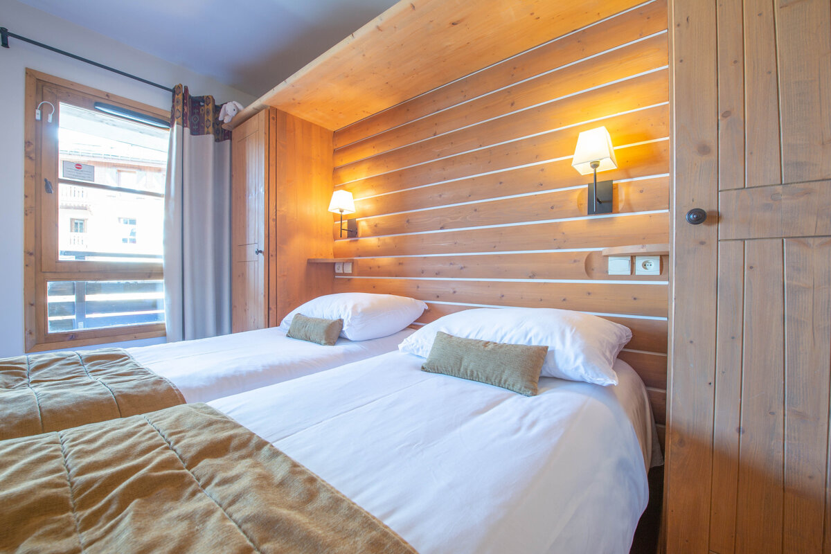 A bedroom with two beds and a wooden wall