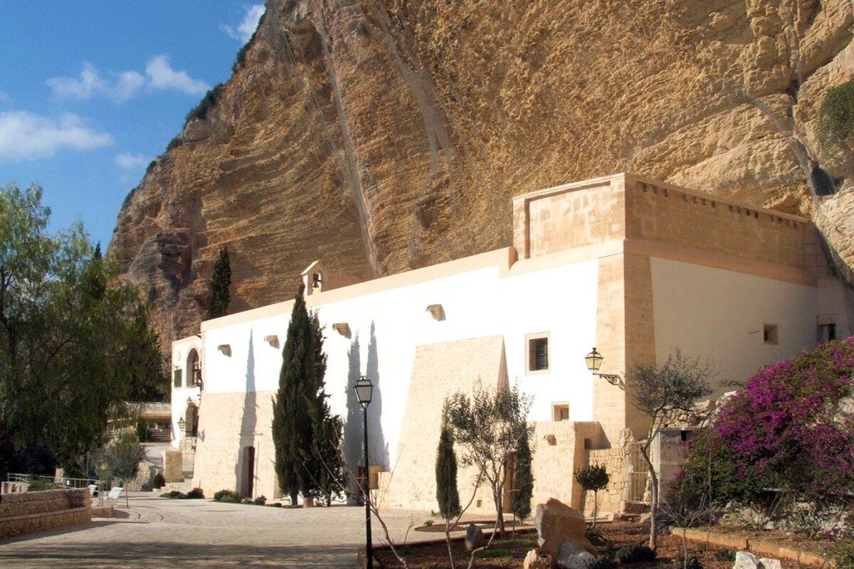 A white building with purple flowers in front of it