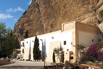A white building with purple flowers in front of it