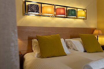 A bed with yellow pillows and lamps above it