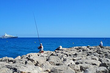 two men fishing off rocks in the sea