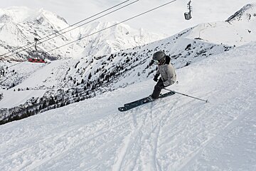 A person skiing down a snowy mountain with a ski lift in the background