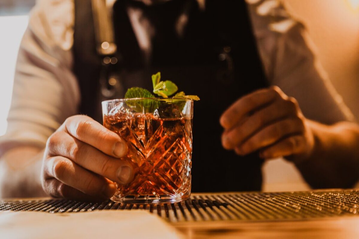 A bartender prepares a drink with ice and mint leaves