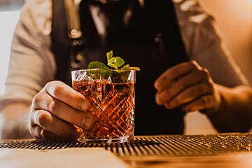 A bartender prepares a drink with ice and mint leaves