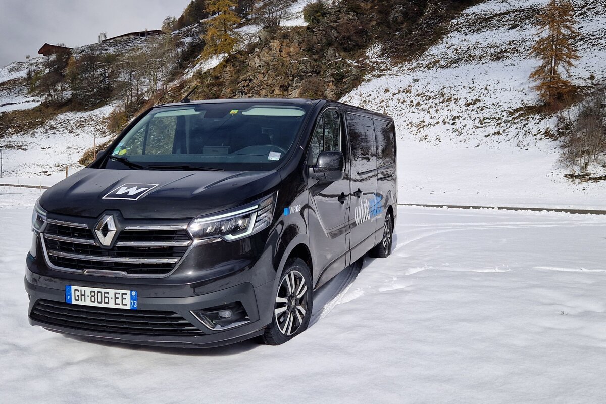 A black van with the license plate gh-806-ee is parked in the snow