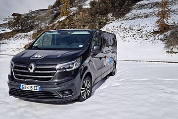 A black van with the license plate gh-806-ee is parked in the snow