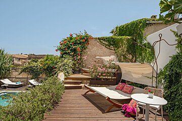 A deck with a couch and a table in front of a pool