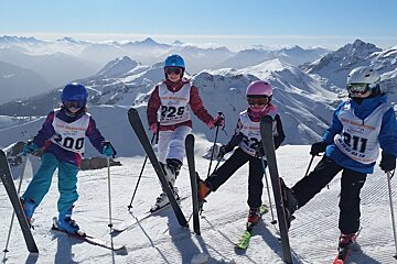 four skiers with one ski up in the air