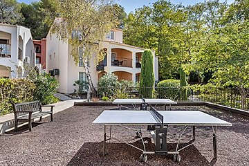 Two ping pong tables in a yard with a building in the background