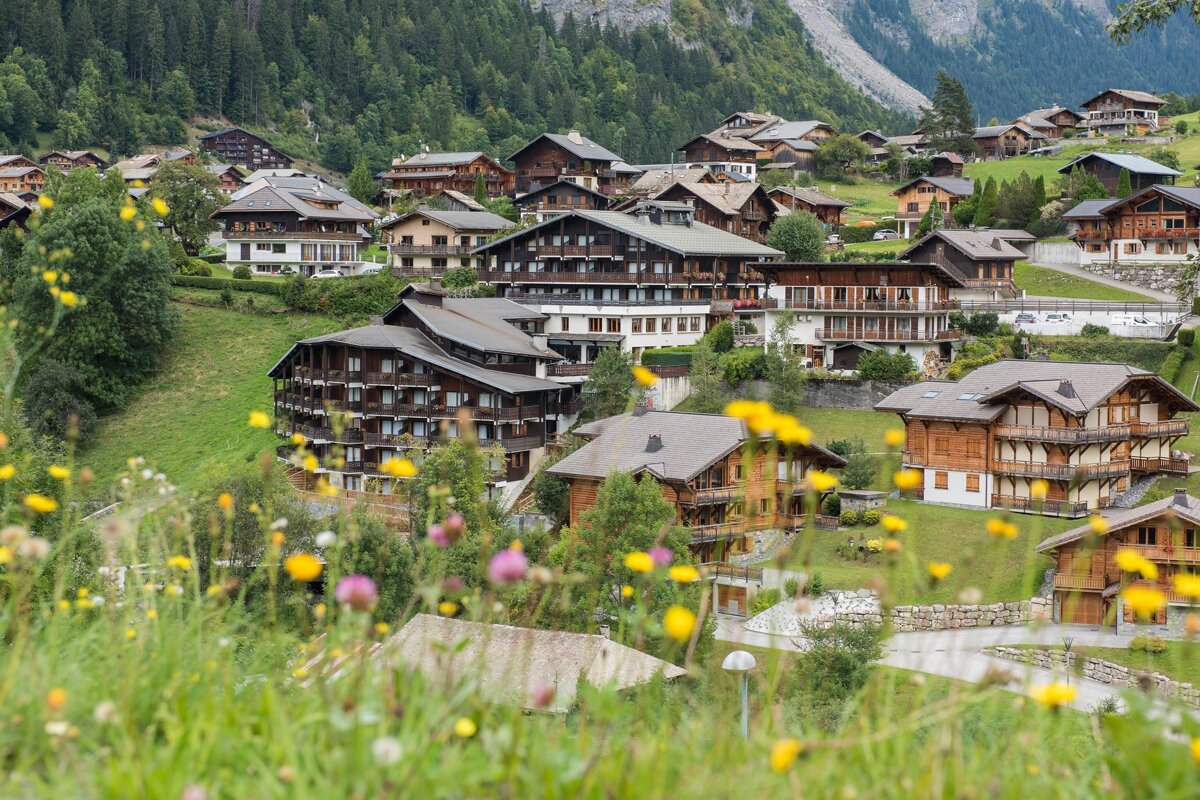 A row of houses on a hillside with flowers in the foreground