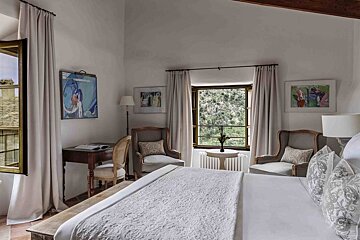 A bedroom with a large bed a desk and chairs