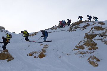 skiers coming down a rocky outcrop