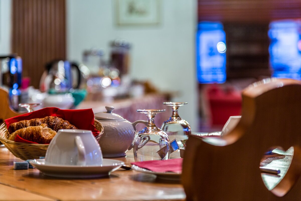 A basket of croissants sits on a table next to cups and glasses