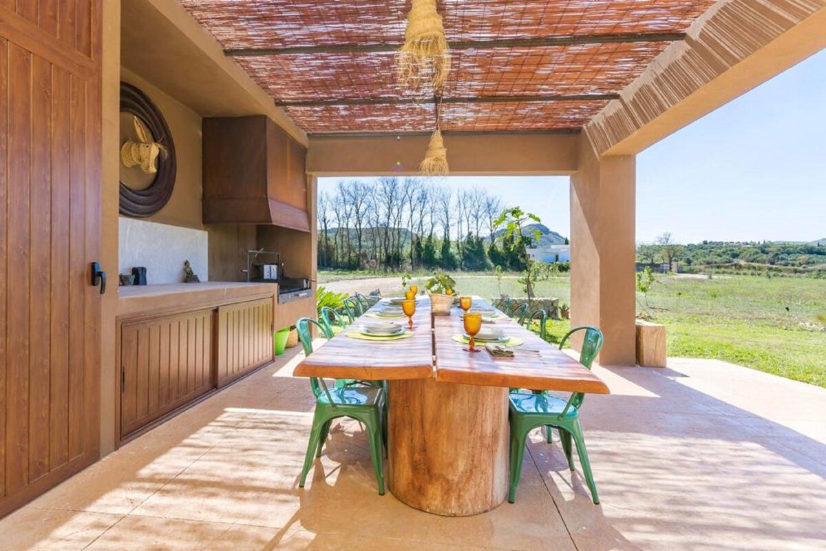 A wooden table with green chairs under a roof
