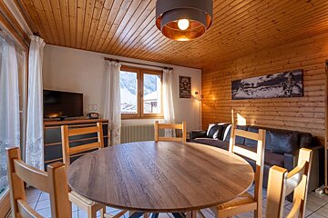 A living room with a table and chairs and a television