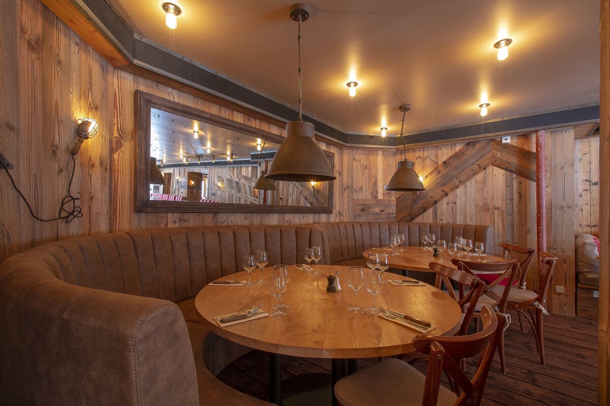 A restaurant with tables and chairs and a mirror on the wall