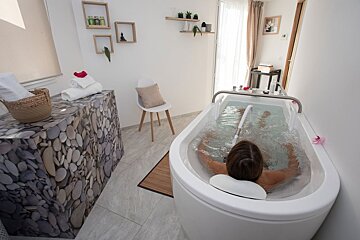 A woman is laying in a bathtub in a bathroom