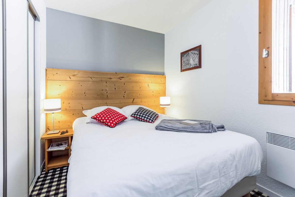 A bedroom with a bed and a wooden headboard