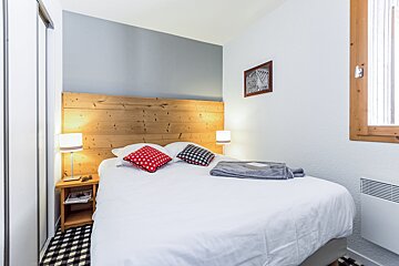 A bedroom with a bed and a wooden headboard