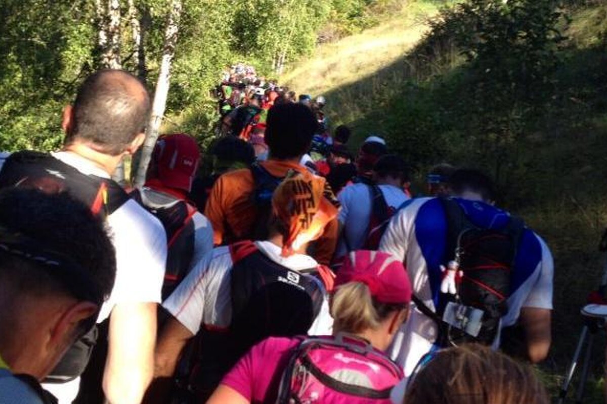 A group of people are walking up a hill and one of their backpacks says salomon