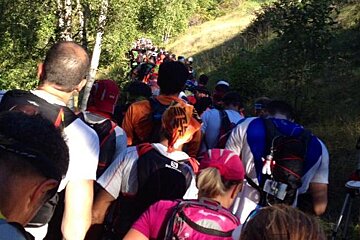 A group of people are walking up a hill and one of their backpacks says salomon