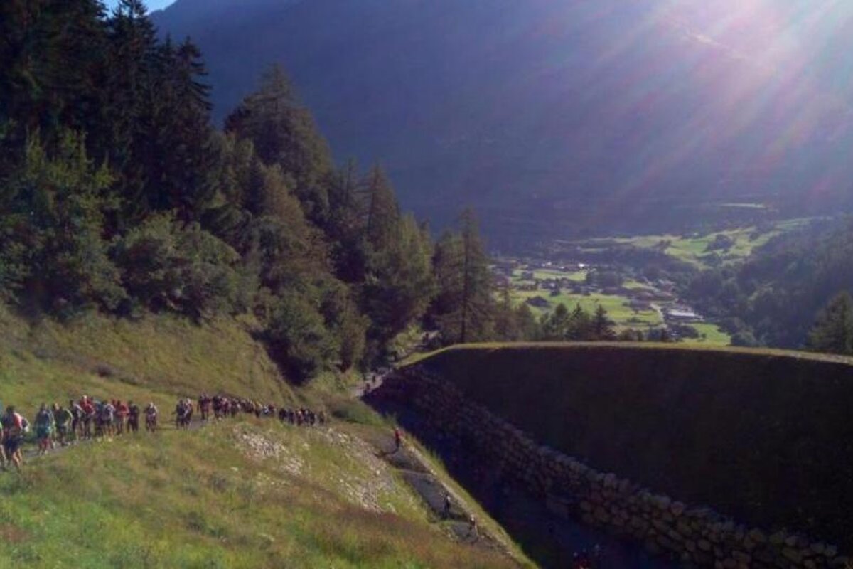 A group of people are walking down a hill in the mountains