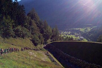 A group of people are walking down a hill in the mountains