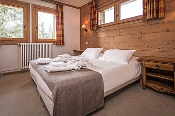 A bedroom with a wooden wall and a bed