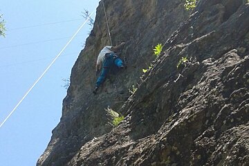 a climber in blue trousers on a rope