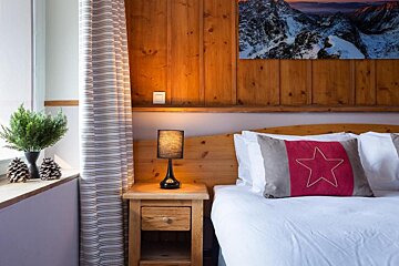 A bedroom with a bed a nightstand and a lamp