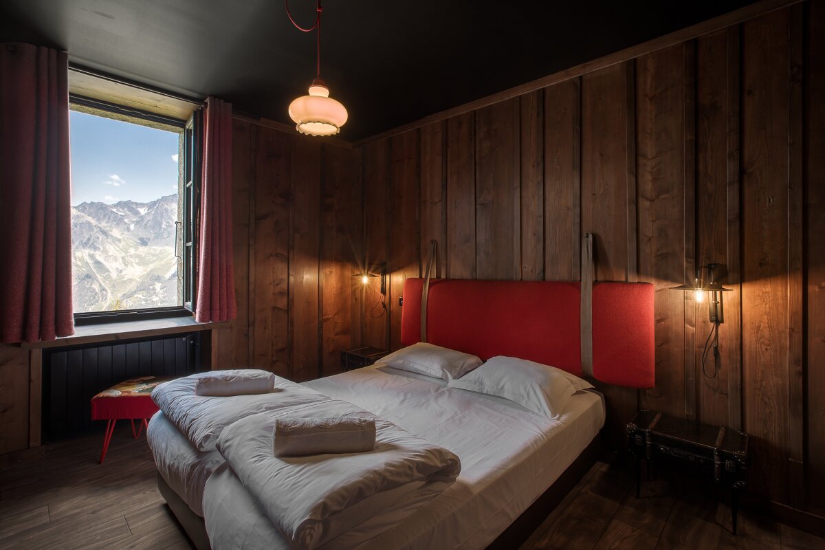 A bedroom with a bed and a window with mountains in the background
