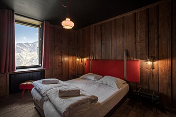 A bedroom with a bed and a window with mountains in the background