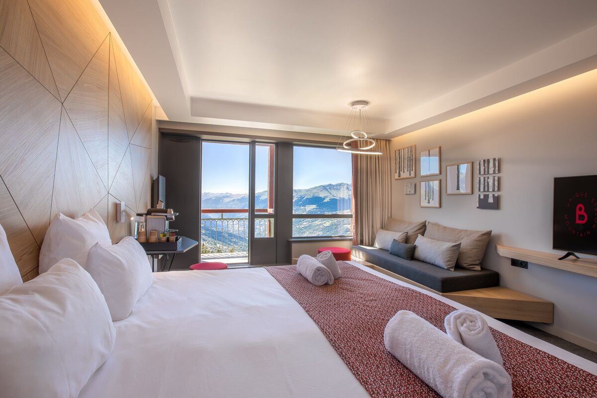 A hotel room with a large bed and a tv with the letter b on it